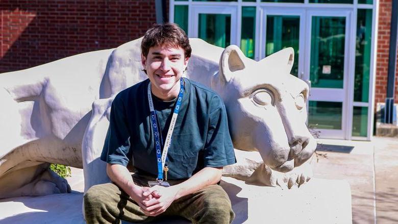 Student smiling by the Greater Allegheny Lion Shrine